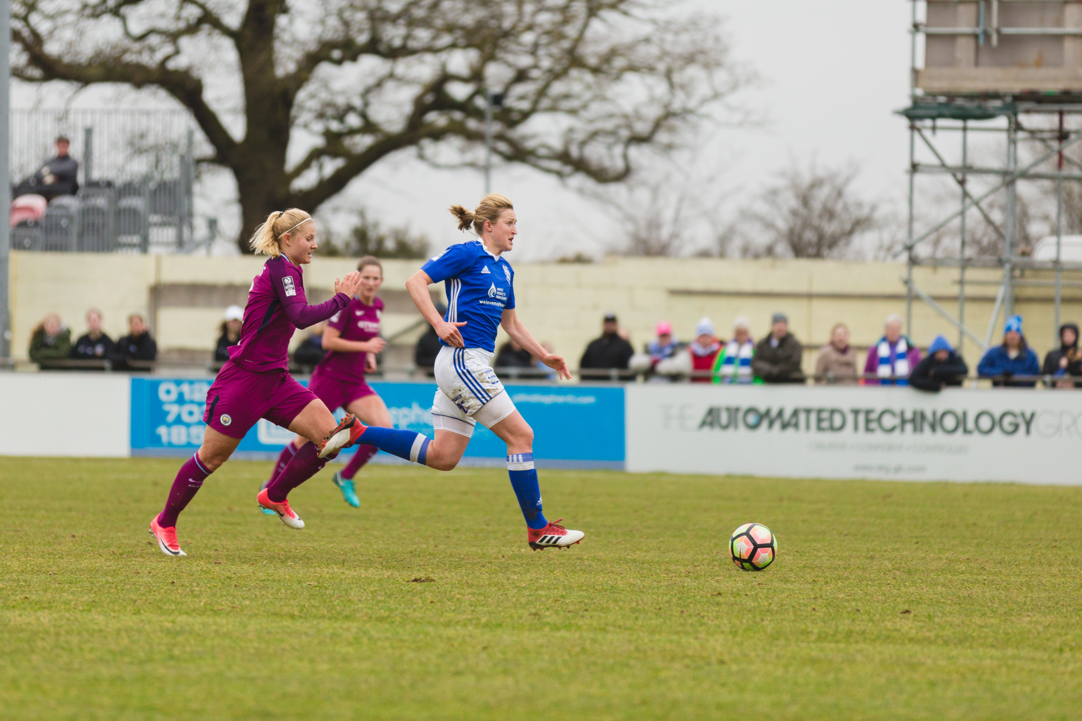Birmingham City Ladies FC player beating out other players to the ball