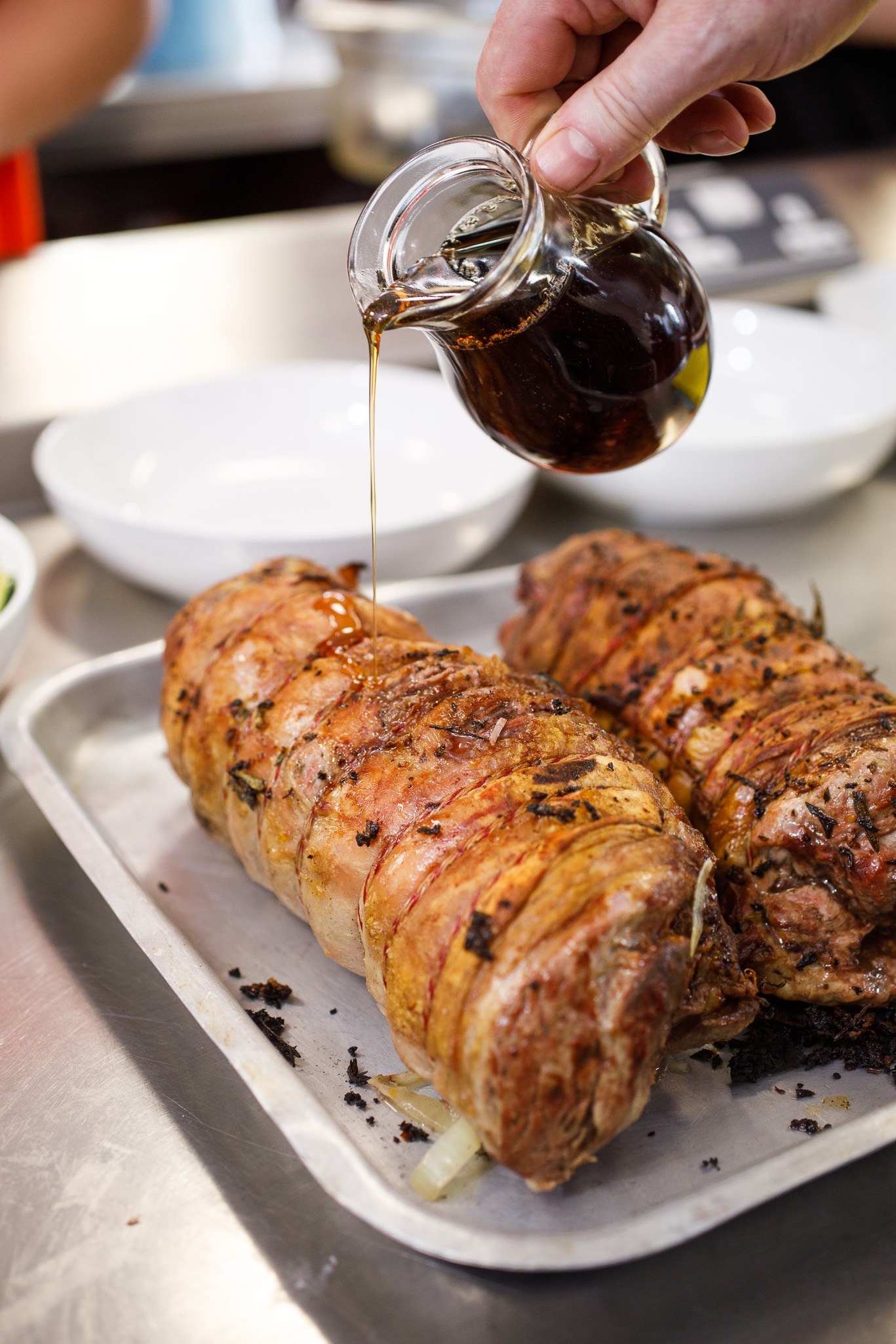 pouring the maple syrup over the marinated joint of lamb 