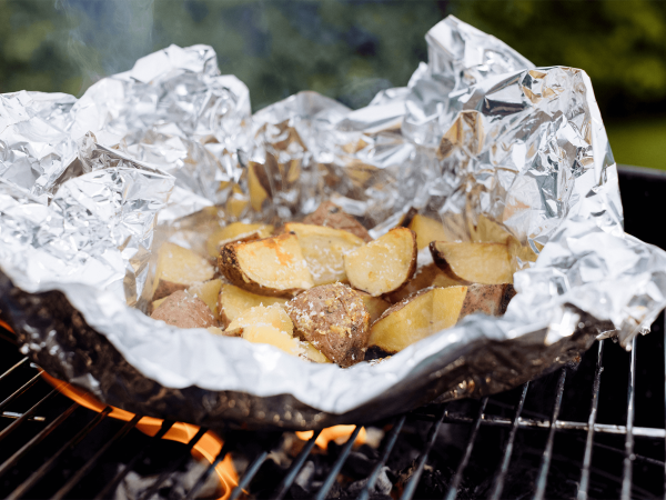 Maple parmesan garlic potato parcels on a grill in tinfoil