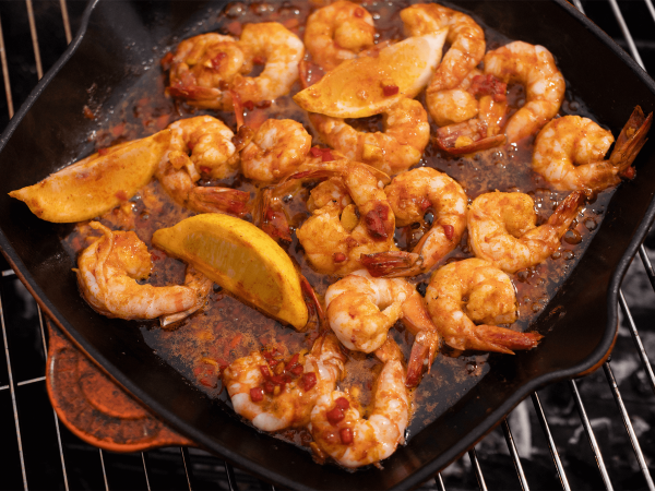 Sizzling maple king prawn in a skillet on a grill